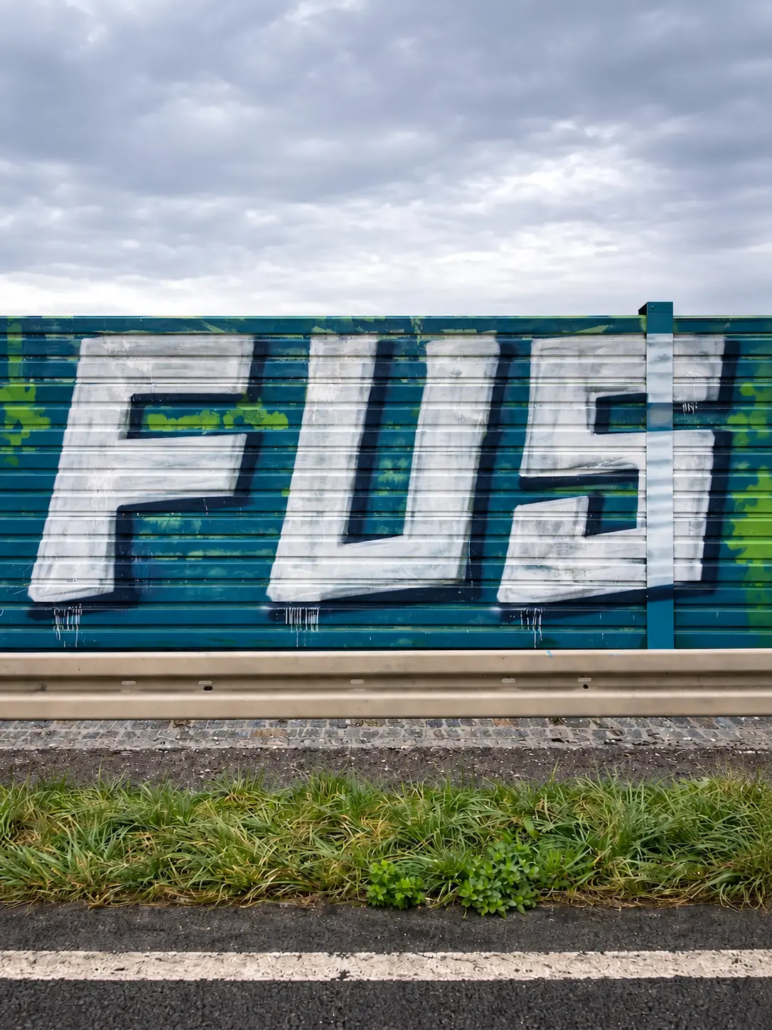 Mit großflächigem Graffiti beschmierte Lärmschutzwand vor der Reinigung