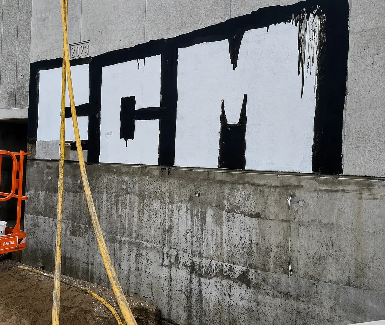 Concrete wall with large-scale graffiti before professional graffiti removal by Muschert.