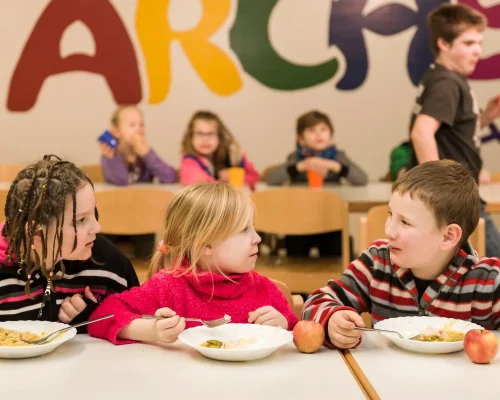 Kinder bei einer gemeinsamen Mahlzeit im Kinder- und Jugendwerk Die Arche