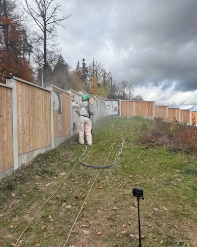 Employee performing graffiti removal on a noise barrier using high-pressure technology