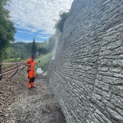 Mitarbeiter bei der Reinigung einer Natursteinmauer im Rahmen der Bauwerkspflege