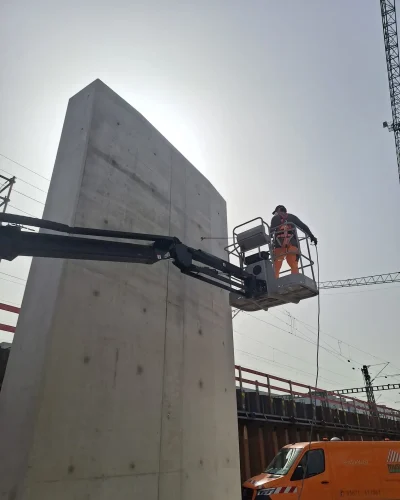 Mitarbeiter bei der Graffitiprophylaxe an einer Beton-Lärmschutzwand mit Hubarbeitsbühne