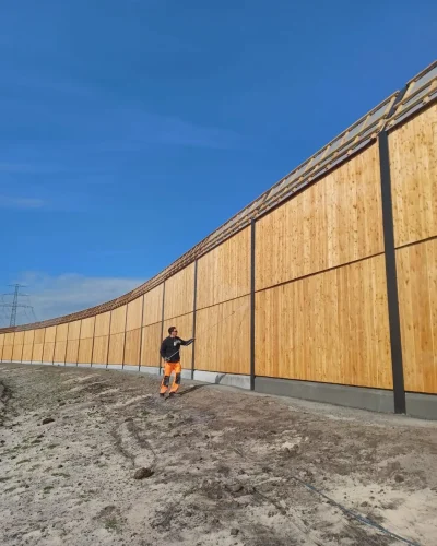 Mitarbeiter vor einer großflächigen hölzernen Lärmschutzwand